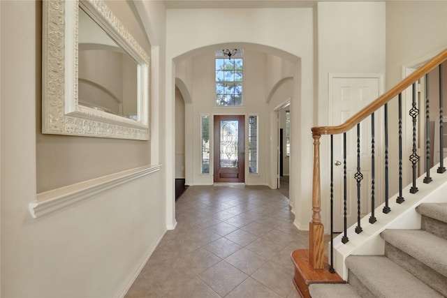 19815 Stanton Lake Dr, Cypress, TX 77433 - entrance foyer featuring arched walkways, baseboards, stairway, light tile patterned floors, and a high ceiling