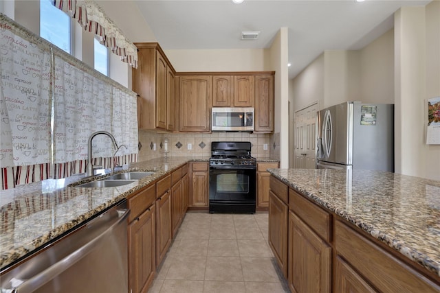 19815 Stanton Lake Dr, Cypress, TX 77433 - kitchen with stainless steel appliances, a sink, dark stone countertops, backsplash, and brown cabinets