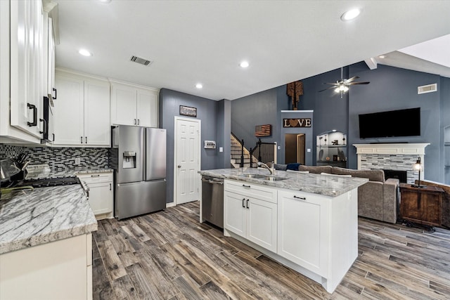 kitchen featuring light stone countertops, white cabinets, a center island with sink, and stainless steel appliances