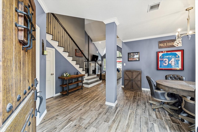 entrance foyer featuring hardwood / wood-style flooring, crown molding, and an inviting chandelier