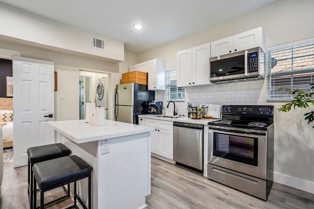 kitchen featuring white cabinets, appliances with stainless steel finishes, a center island, and sink