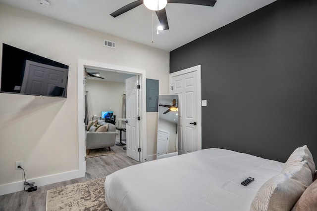 bedroom with light wood-type flooring, electric panel, and ceiling fan