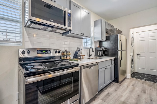 kitchen featuring gray cabinetry, sink, stainless steel appliances, and light wood-type flooring