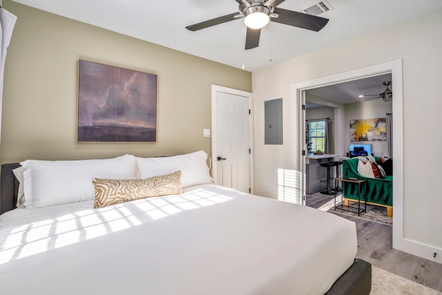 bedroom with electric panel, ceiling fan, and light hardwood / wood-style floors