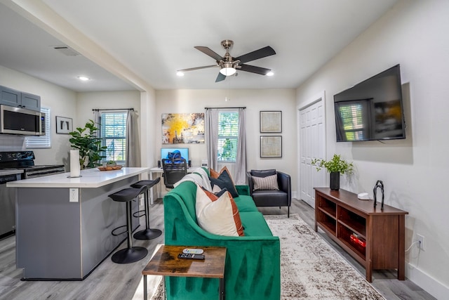 living room featuring ceiling fan, plenty of natural light, and light wood-type flooring