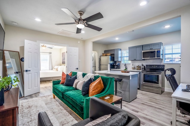 living room with light hardwood / wood-style flooring and ceiling fan