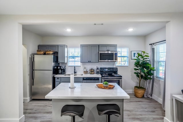 kitchen with light stone countertops, light hardwood / wood-style flooring, a healthy amount of sunlight, and appliances with stainless steel finishes