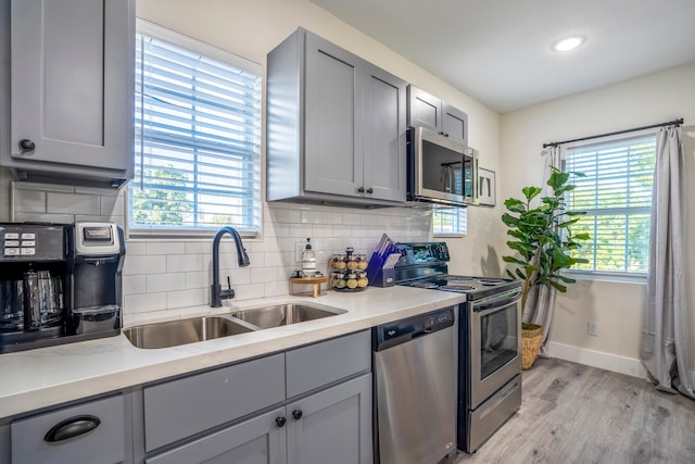 kitchen featuring gray cabinetry, sink, stainless steel appliances, and light hardwood / wood-style floors