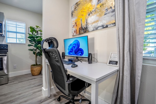 office space with light hardwood / wood-style floors and a healthy amount of sunlight