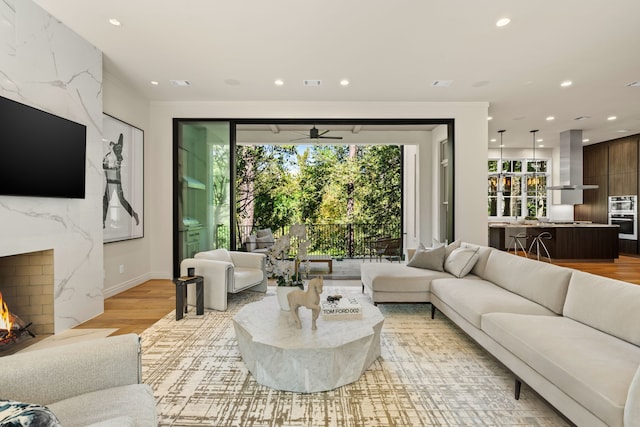 living room featuring a fireplace, light hardwood / wood-style floors, and ceiling fan