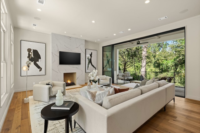 living room featuring hardwood / wood-style floors, ceiling fan, and a premium fireplace