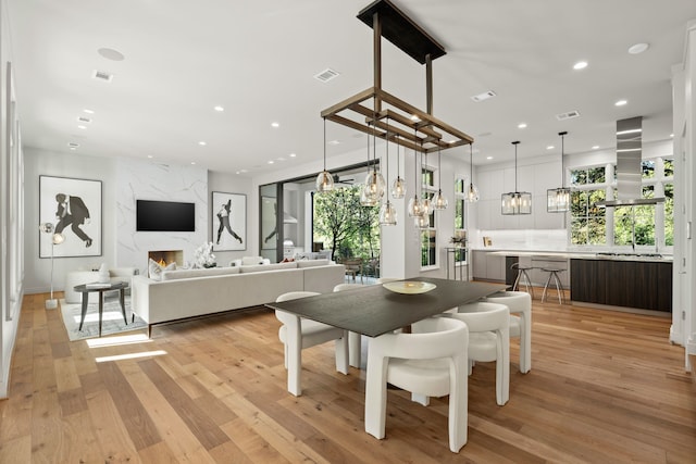 dining room featuring a premium fireplace, plenty of natural light, and light hardwood / wood-style floors