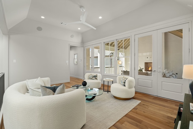 living room featuring lofted ceiling, ceiling fan, french doors, and light hardwood / wood-style flooring