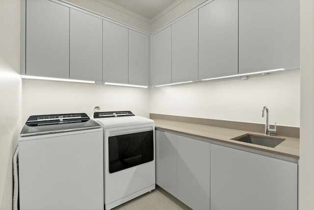 washroom featuring washing machine and clothes dryer, sink, and cabinets