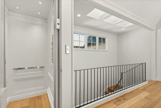 hall with elevator, hardwood / wood-style floors, and a skylight