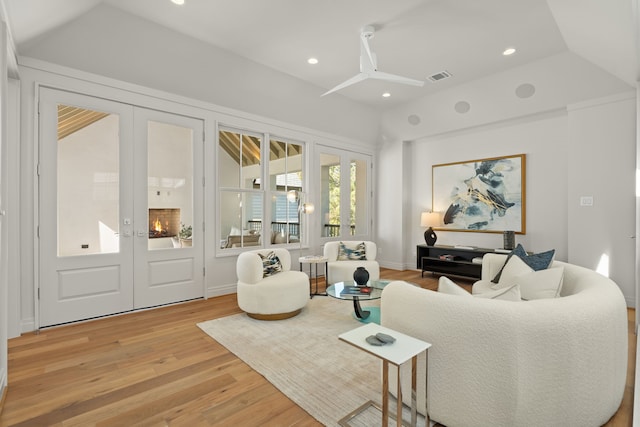 living room featuring ceiling fan, light hardwood / wood-style floors, a tray ceiling, and french doors