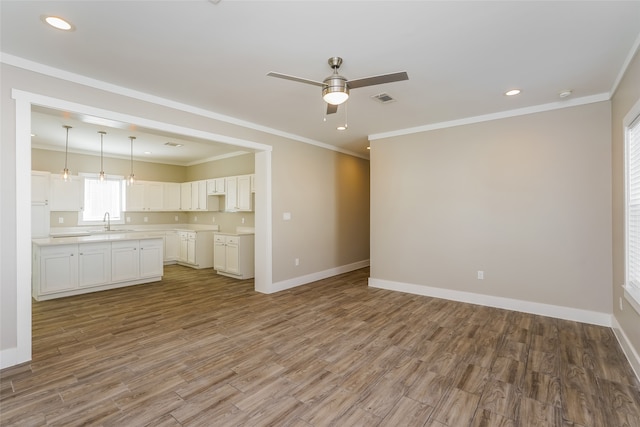 unfurnished living room with sink, wood-type flooring, and crown molding