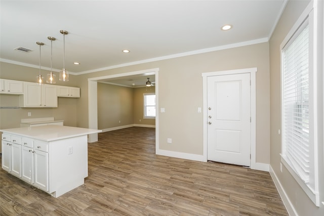 kitchen featuring a center island, light wood-type flooring, decorative light fixtures, white cabinets, and ornamental molding