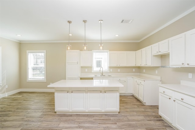 6609 Greenhurst St, Houston, TX 77091 - kitchen with a kitchen island, light wood-type flooring, white cabinetry, light countertops, and crown molding