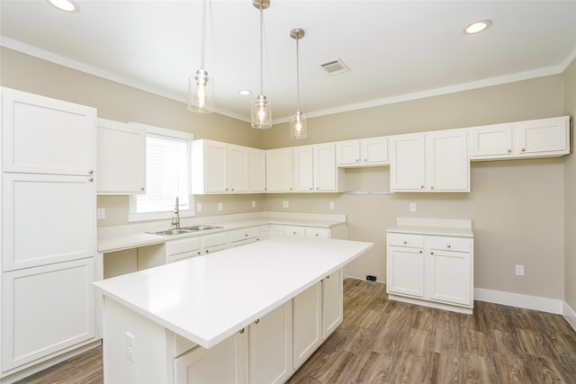 kitchen with white cabinets, sink, crown molding, and a kitchen island