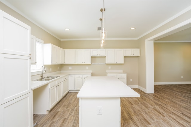 kitchen featuring sink, decorative light fixtures, a center island, light hardwood / wood-style floors, and white cabinetry