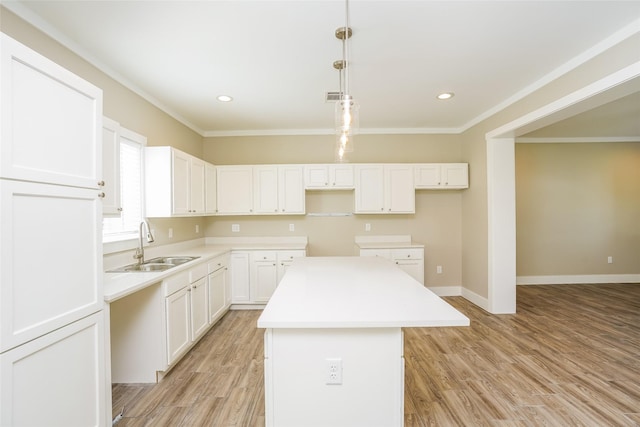 6609 Greenhurst St, Houston, TX 77091 - kitchen with a sink, a kitchen island, crown molding, light wood-style floors, and white cabinetry