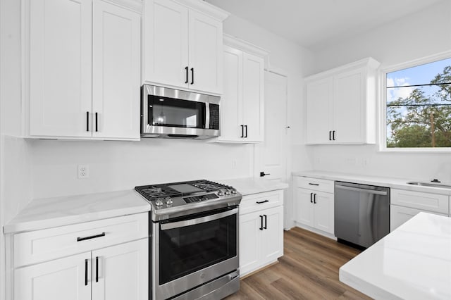 kitchen featuring light stone counters, dark hardwood / wood-style flooring, white cabinets, and stainless steel appliances