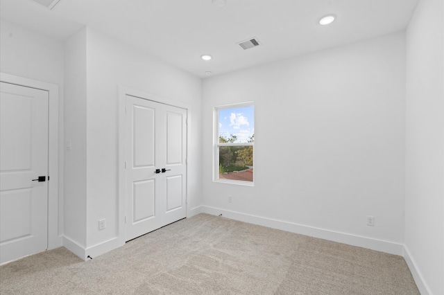 unfurnished bedroom featuring light carpet and a closet