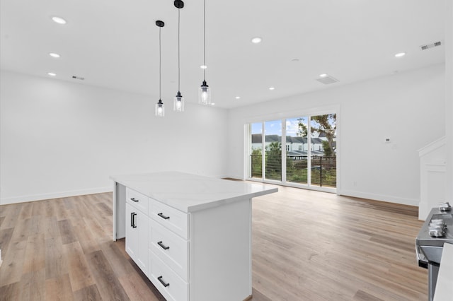 kitchen featuring light stone counters, decorative light fixtures, light hardwood / wood-style flooring, white cabinets, and a kitchen island