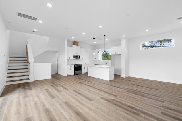 4124 Bucks St, Houston, TX 77020 - unfurnished living room with recessed lighting, light wood-style floors, and stairs
