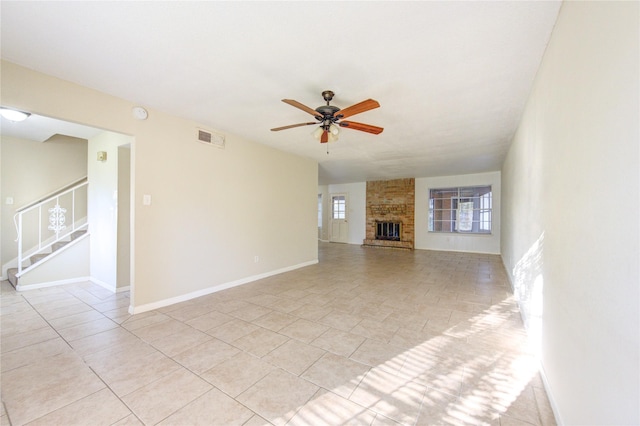 unfurnished living room with a brick fireplace, light tile patterned floors, and ceiling fan