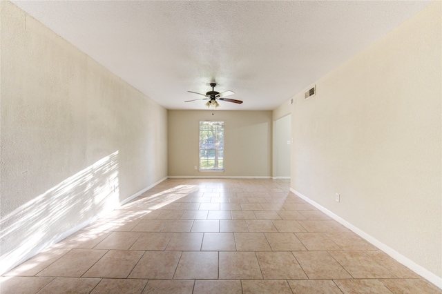 unfurnished room with ceiling fan, light tile patterned floors, and a textured ceiling