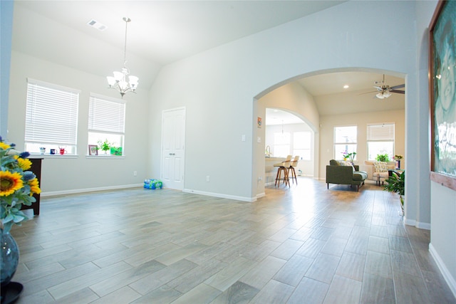 interior space featuring ceiling fan with notable chandelier, lofted ceiling, and light wood-type flooring