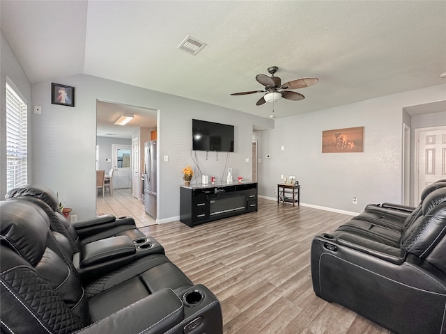 living room with ceiling fan, lofted ceiling, light hardwood / wood-style floors, and a textured ceiling