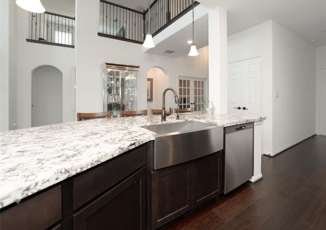 kitchen featuring light stone counters, dark wood-type flooring, sink, decorative light fixtures, and dishwasher