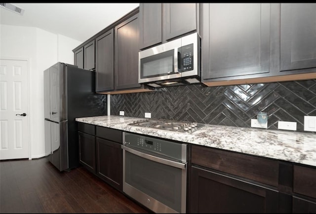 kitchen featuring light stone countertops, dark brown cabinets, stainless steel appliances, and dark wood-type flooring