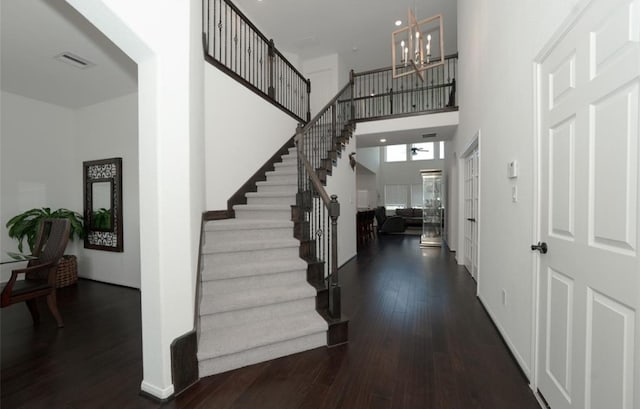 entrance foyer with a towering ceiling, dark wood-type flooring, and a notable chandelier