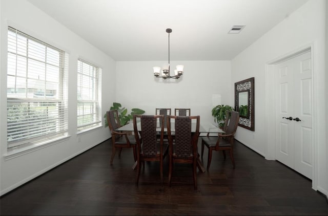 dining space with dark hardwood / wood-style flooring and a chandelier