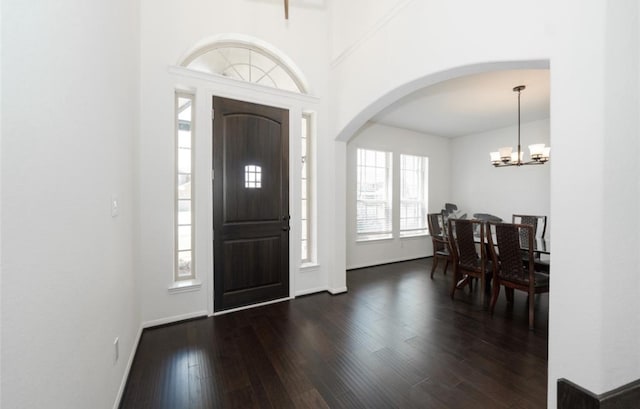 entryway with a notable chandelier, a healthy amount of sunlight, and dark wood-type flooring