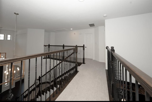 corridor with dark colored carpet and an inviting chandelier