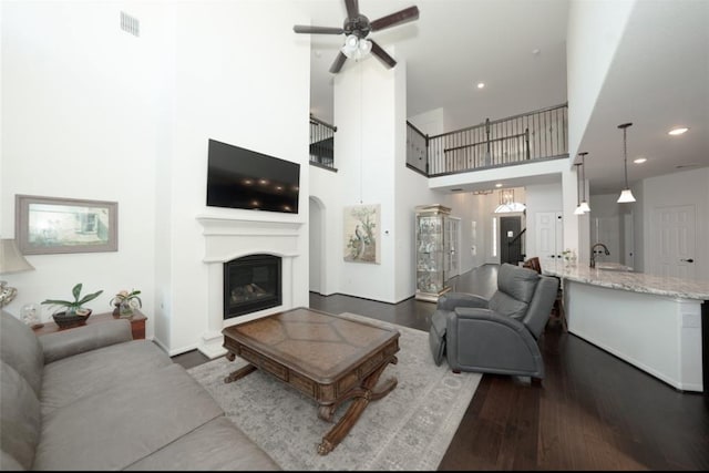 living room featuring ceiling fan, sink, dark wood-type flooring, and a high ceiling