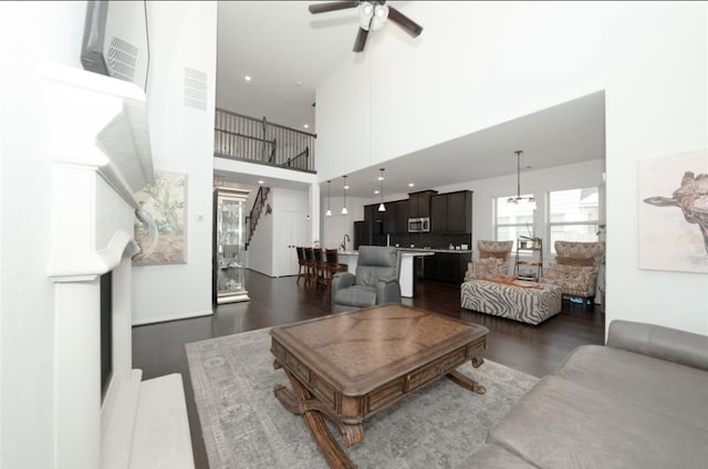 living room featuring ceiling fan, dark wood-type flooring, and a high ceiling