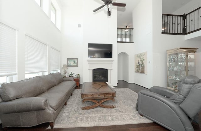 living room with ceiling fan, dark hardwood / wood-style flooring, and a towering ceiling