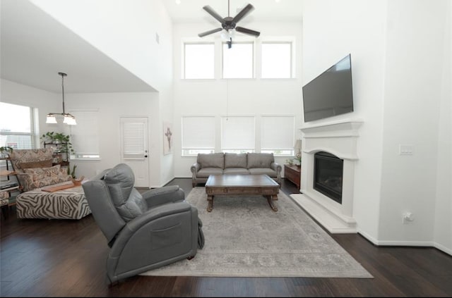 living room featuring dark hardwood / wood-style floors, ceiling fan, and a high ceiling