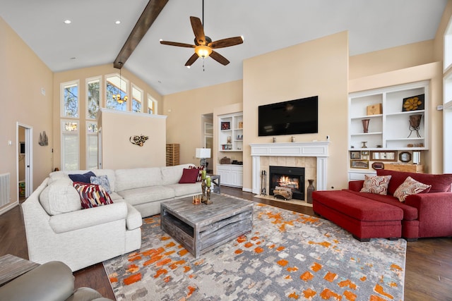 living room featuring a tile fireplace, beam ceiling, dark hardwood / wood-style floors, and ceiling fan