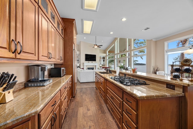 kitchen with light stone countertops, dark wood-type flooring, sink, black gas cooktop, and lofted ceiling