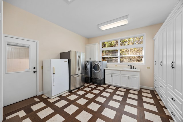 laundry room featuring cabinets, independent washer and dryer, and sink