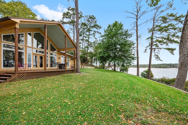 view of yard with a deck with water view and french doors