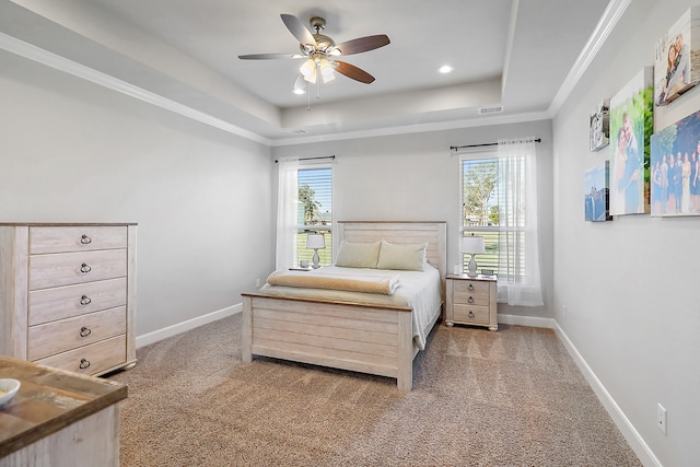 carpeted bedroom with a tray ceiling, ceiling fan, and crown molding