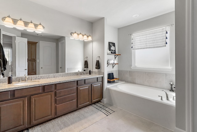 bathroom with tile patterned floors, vanity, a healthy amount of sunlight, and a tub